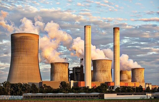Elektrizit&auml;tswerk mit dampfenden Schornsteinen und blauem, zart bew&ouml;lktem Himmel.