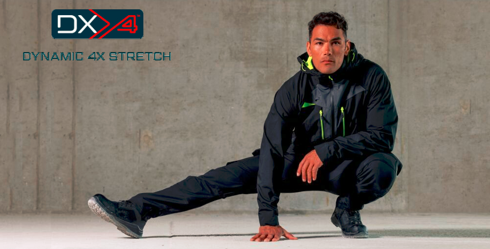 Mann in schwarzer, sportlicher Arbeitskleidung mit neonfarbenen Akzenten in Hockposition vor einer grauen Betonwand. Oben links das Logo ‚DX4 Dynamic 4X Stretch‘.