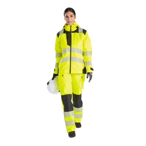 Frau in warngelber Arbeitskleidung. Sie hat einen Helm in der Hand und blickt direkt in die Kamera. Ein Link zur PW3 Warnschutz-Regenhose f&uuml;r Damen PW386 ist hinterlegt.