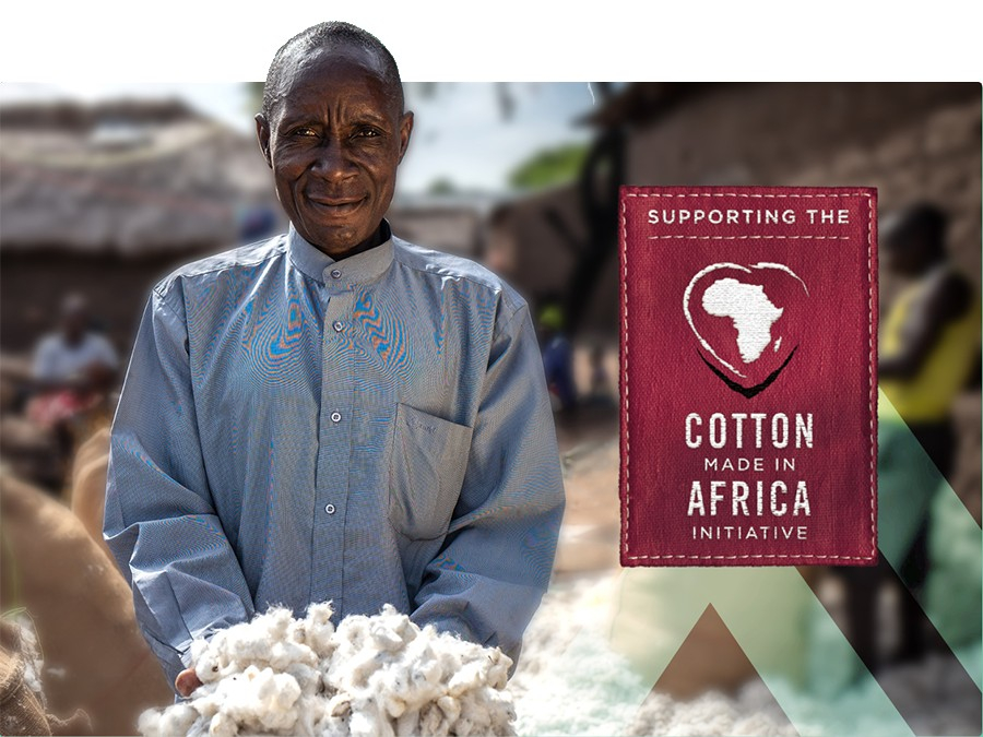 Afrikanischer Bauer, der ein blaues Hemd trägt und eine Handvoll Baumwolle präsentiert. Ein tiefrotes Schild mit der Aufschrift "Supporting the Cotton Made In Africa Initiative" befindet sich in der rechten Bildhälfte.
