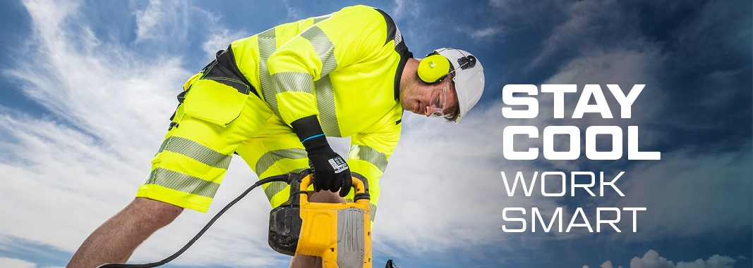 Arbeiter mit Helm und Gehörschutz in warngelber Sommer-Arbeitskleidung beim Arbeiten mit dem Presslufthammer, im Hintergund blauer, leicht bewölkter Himmel, Bagger und Stapel mit Holzbohlen.