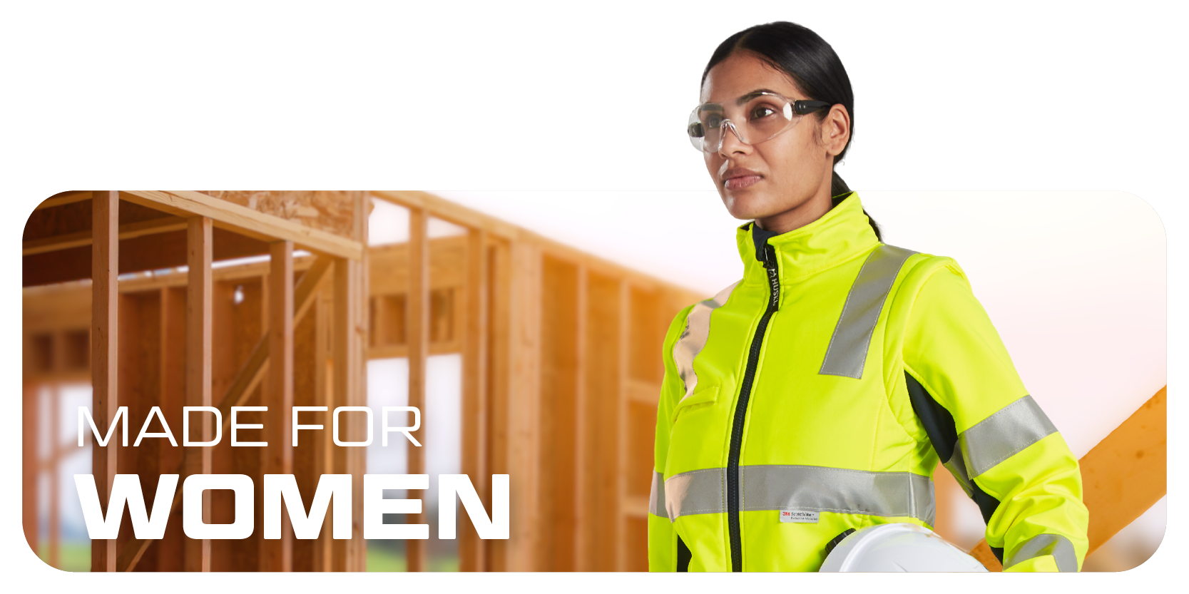 Dame mit Brille, Helm und Warnkleidung, im Hintergrund Holzwände in Ständerbauweise.