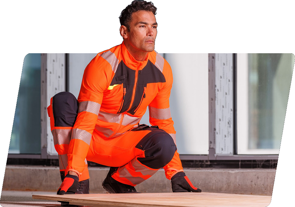 Ein dunkelhaariger Arbeiter in oranger Warnschutzkleidung, der eine Holzplatte vom Boden anhebt. Hinterlegt ist ein Link zu unserer DX4-Kollektion.
