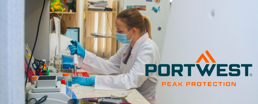 Wissenschaftlerin im Labor trägt weißen Laborkittel, blaue Handschuhe und eine Maske, während sie mit einer Pipette arbeitet. Portwest-Logo mit Slogan ‚Peak Protection‘ im Vordergrund.