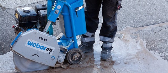 Arbeiter in Warnschutzhose mit Sicherheitsschuhen im Straßenbau.