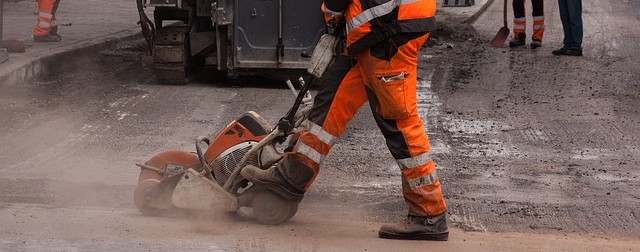 Arbeiter mit Warnschutzhose in Orange beim Arbeiten im Straßenbau.